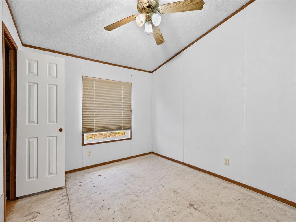 Room interior featuring panelled walls, a six-panel door, a multi-light ceiling fan, and a single window with pleated shades