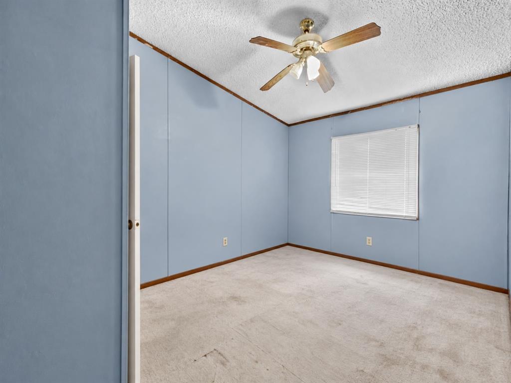 Room featuring neutral carpeting, panel walls, a ceiling fan with integrated light fixture, and a window with blinds