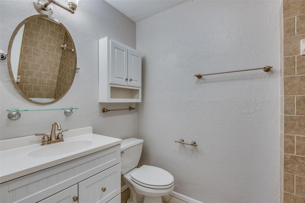 Bathroom featuring a white vanity cabinet with an integrated basin, oval wall mirror, wall-mounted medicine cabinet, and tiled shower surround