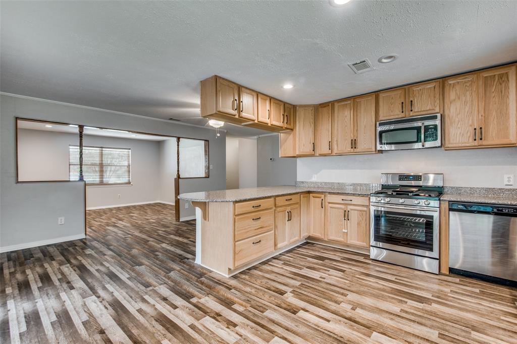 Kitchen featuring natural wood-finish cabinetry, stone-style countertops, stainless steel appliances, recessed lighting, and wood-finish flooring Kitchen featuring natural wood-finish cabinetry, stone-style countertops, stainless steel appliances, recessed lighting, and wood-finish flooring