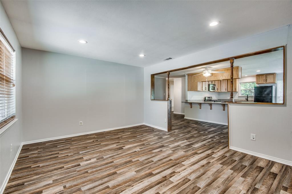 Open-concept area featuring wood-finish flooring, recessed lighting, a breakfast bar with wood-trimmed partition, and kitchen cabinetry Open-concept area featuring wood-finish flooring, recessed lighting, a breakfast bar with wood-trimmed partition, and kitchen cabinetry