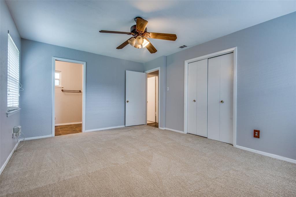 Neutral-toned interior featuring wall-to-wall carpeting, dual-door closet storage, and a ceiling-mounted fan with integrated light fixture Neutral-toned interior featuring wall-to-wall carpeting, dual-door closet storage, and a ceiling-mounted fan with integrated light fixture