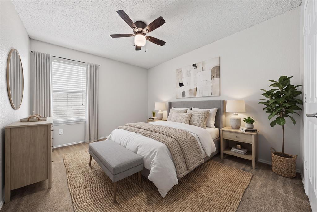 Neutral-toned room featuring wall-to-wall carpeting, window with blinds, and a ceiling-mounted fan with light fixture