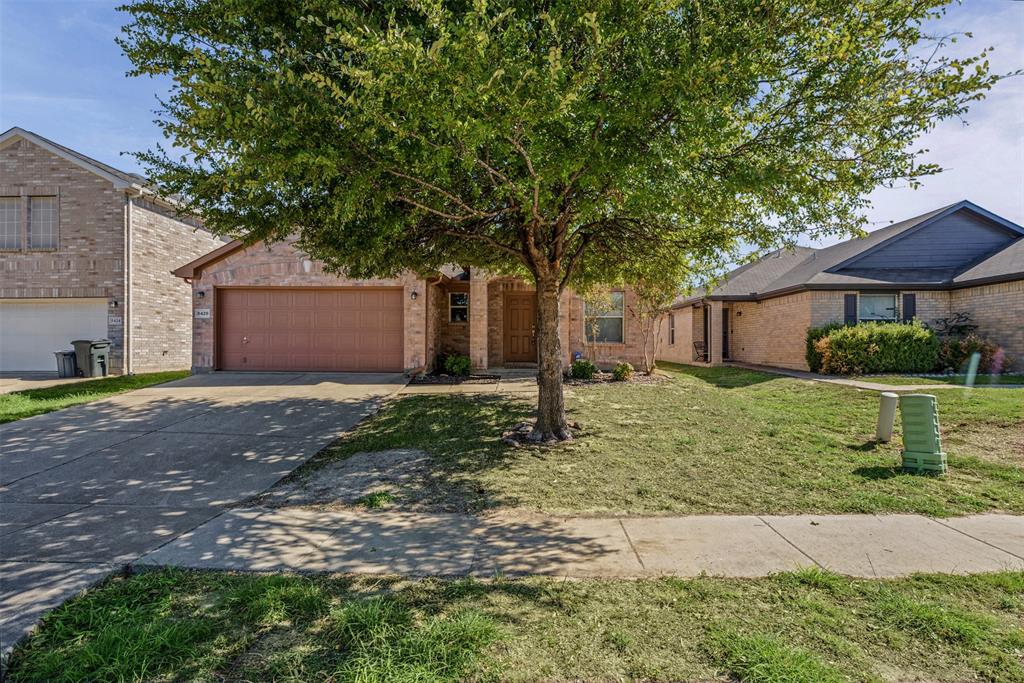 Brick exterior featuring an attached two-car garage, concrete driveway, and front-facing mature tree Brick exterior featuring an attached two-car garage, concrete driveway, and front-facing mature tree