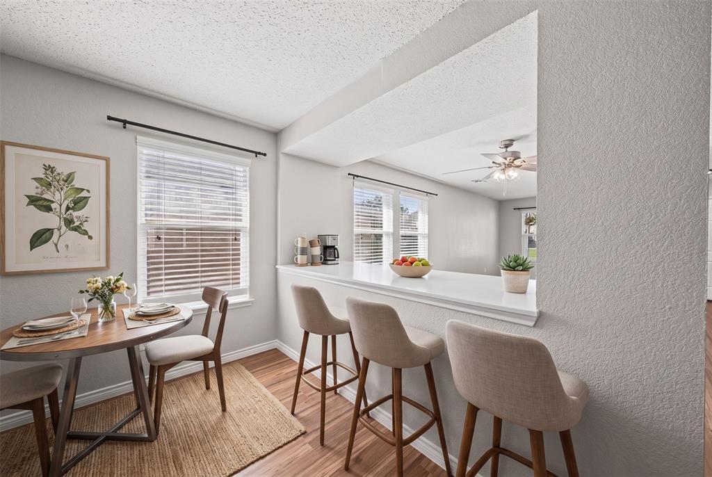 Breakfast nook featuring a pass-through window with a quartz breakfast bar, wood-finish flooring, and horizontal window blinds Breakfast nook featuring a pass-through window with a quartz breakfast bar, wood-finish flooring, and horizontal window blinds