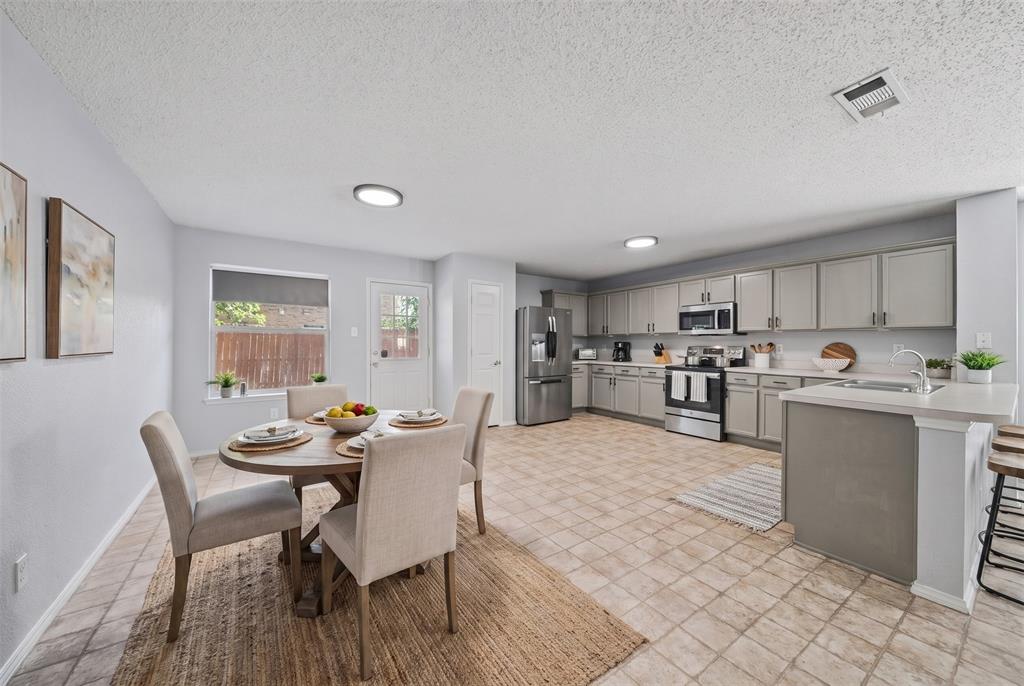 Kitchen featuring grey shaker-style cabinetry, a central island with an integrated stainless steel sink, tile flooring, and stainless steel appliances