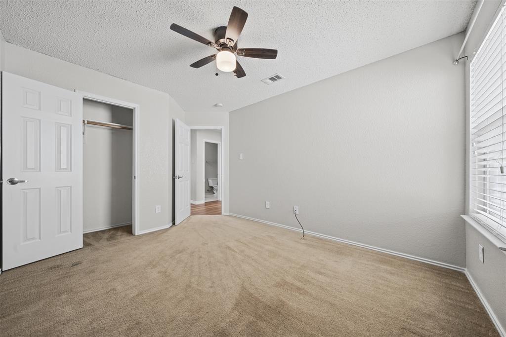 Neutral-toned carpeting, ceiling fan with integrated lighting, and horizontal window blinds