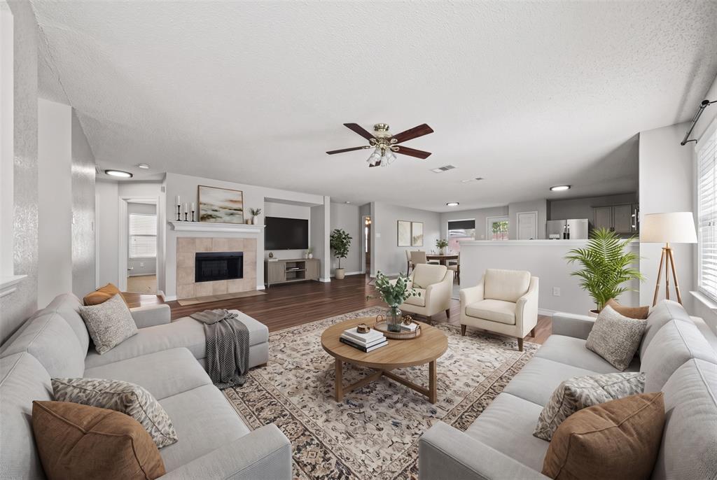 Living area featuring wood-finish flooring, a fireplace with a neutral tile surround, a central ceiling fan, and recessed lighting