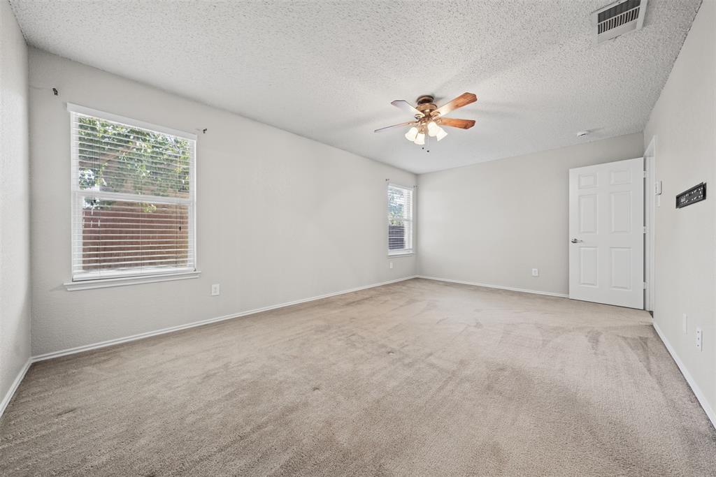 Neutral interior space featuring carpeted flooring, two windows with horizontal blinds, and a ceiling fan with integrated lighting