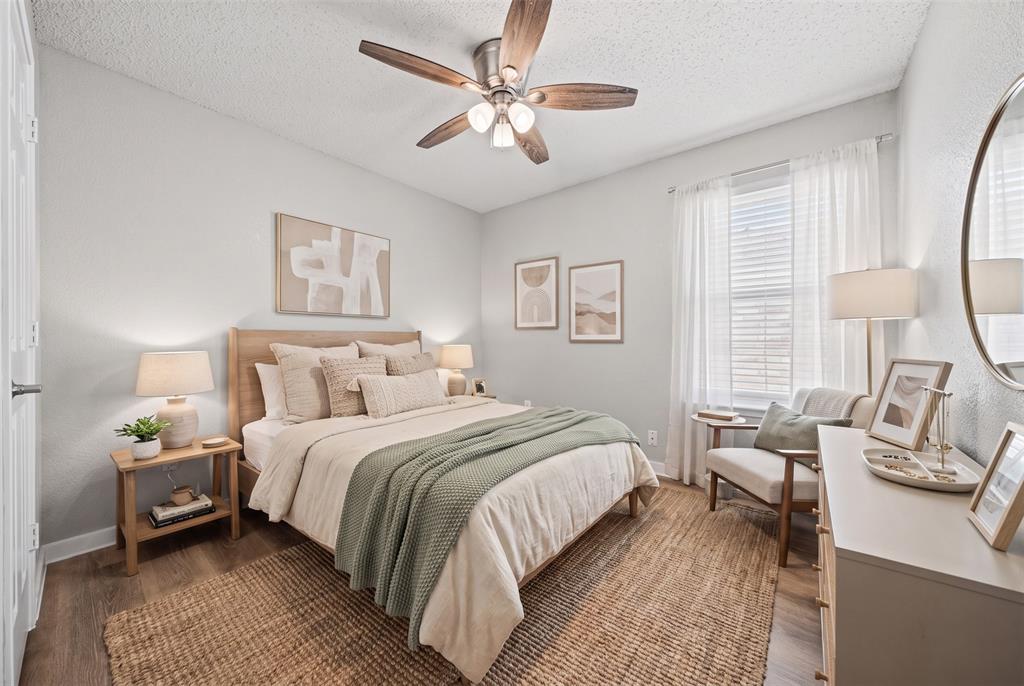 Room featuring wood-finish flooring, a central multi-blade ceiling fan with integrated lighting, and a large window with vertical blinds