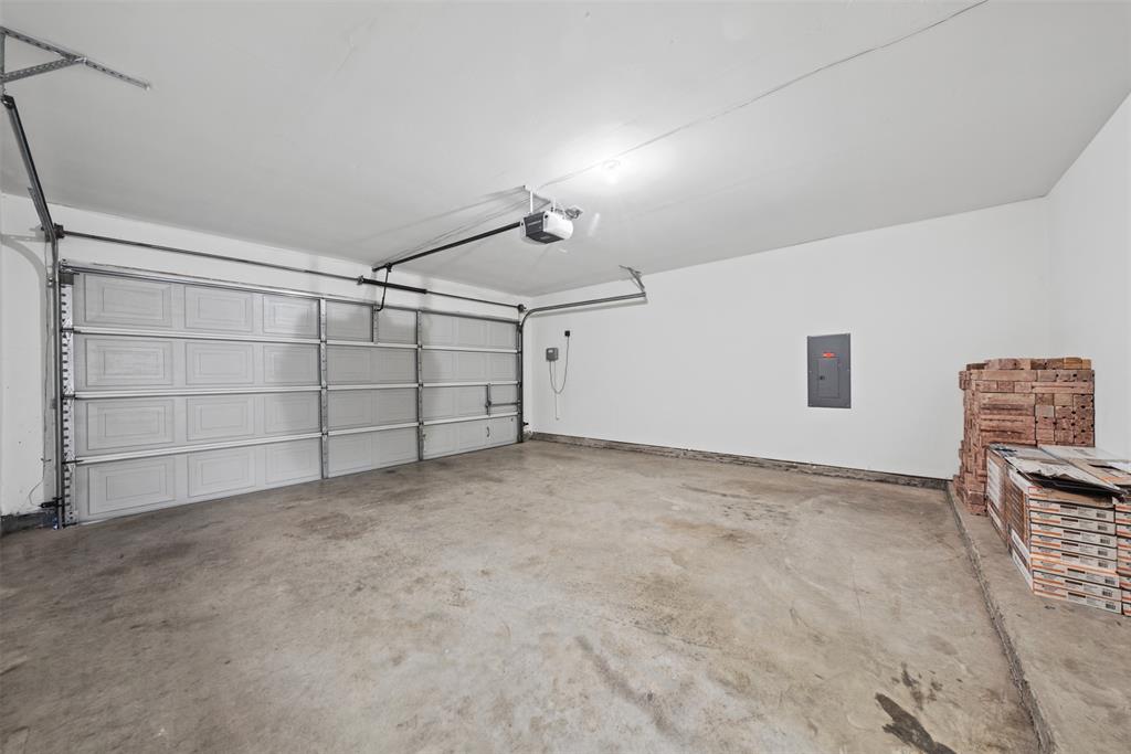 Multi-car garage featuring a sectional metal overhead door, concrete flooring, and an integrated electrical service panel