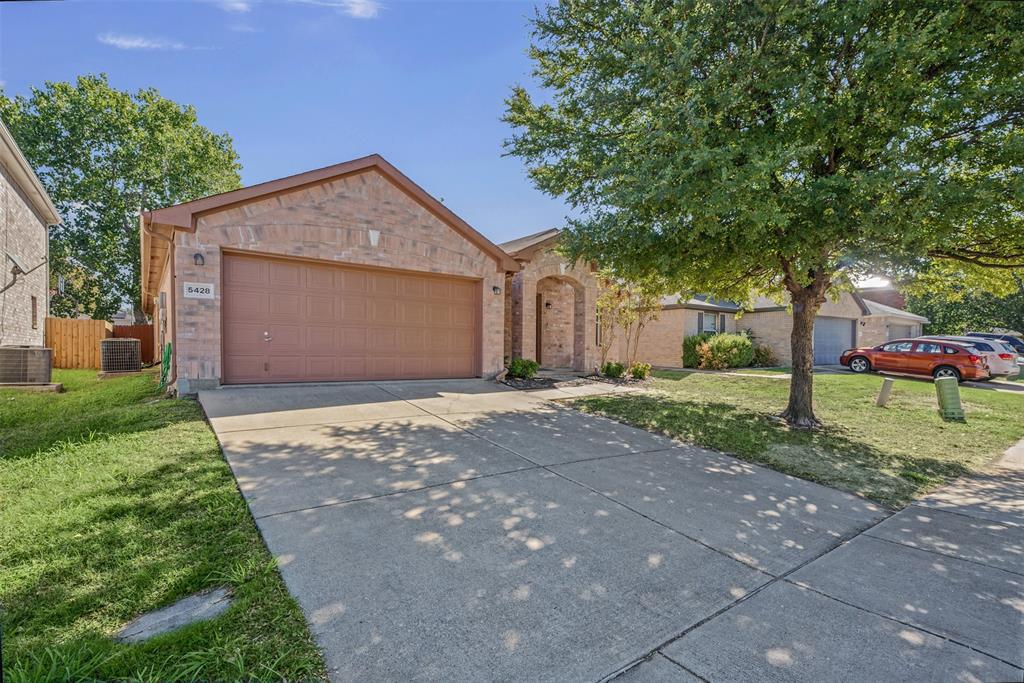 Single-story brick exterior featuring a multi-car garage, concrete driveway, and arched entryway Single-story brick exterior featuring a multi-car garage, concrete driveway, and arched entryway