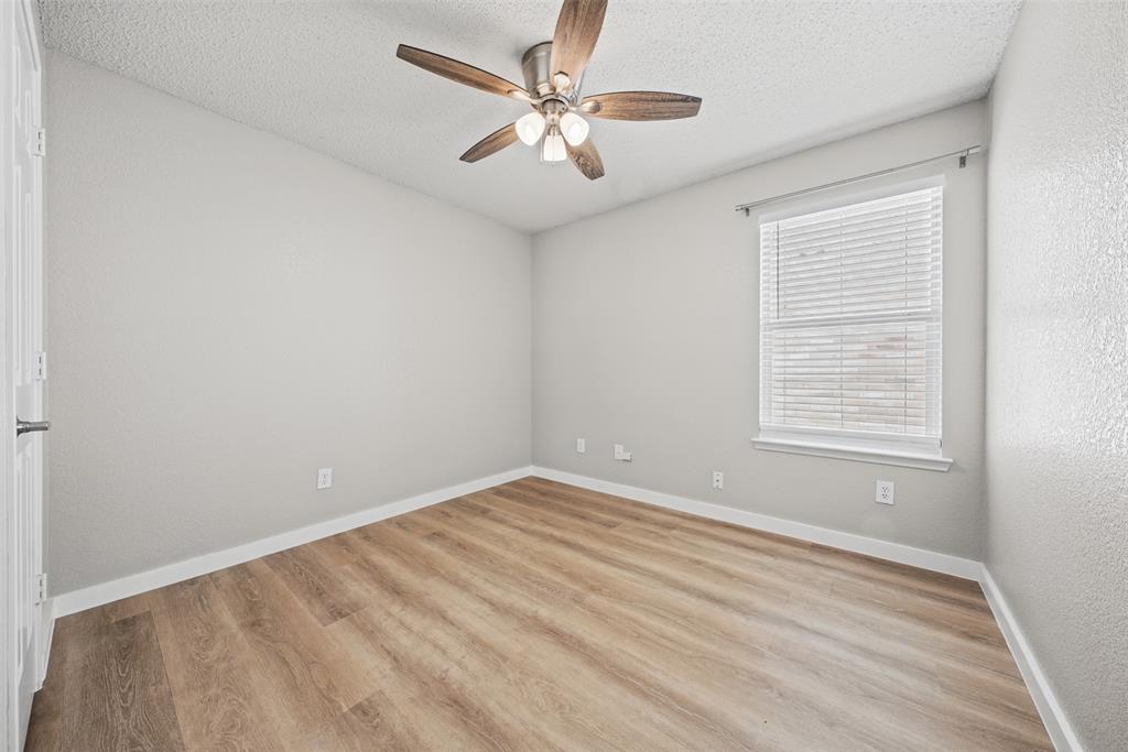 Wood-finish flooring, neutral wall tones, multi-blade ceiling fan with integrated lighting, and horizontal window blinds
