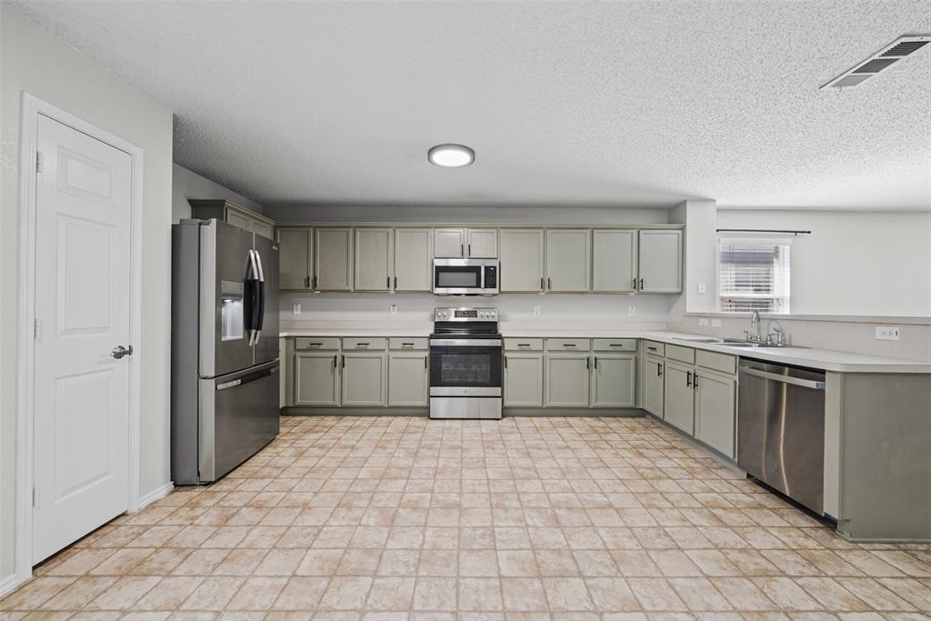 Kitchen featuring light-toned cabinetry, stainless steel appliances, ceramic tile flooring, and a peninsula with a stainless steel sink