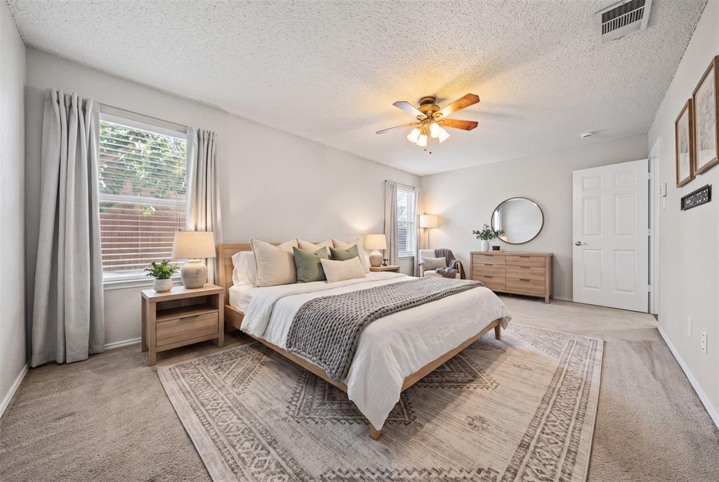 Spacious room featuring neutral carpeting, a central ceiling fan with integrated lighting, multiple windows, and a classic six-panel door
