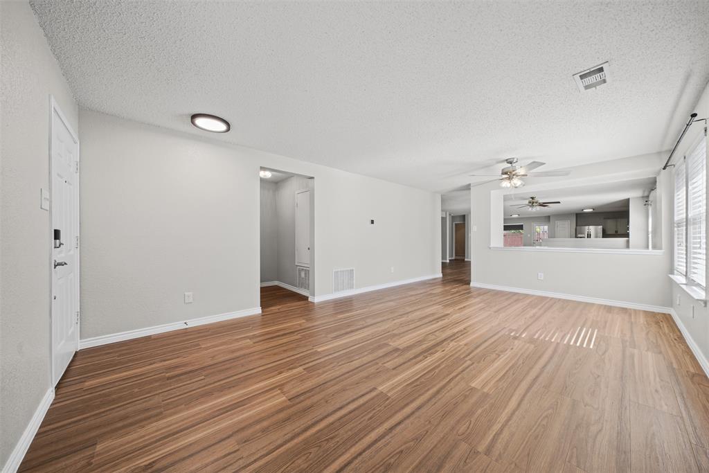 Spacious interior featuring wood-finish flooring, neutral wall paint, recessed ceiling lighting, a multi-blade ceiling fan, and a pass-through opening Spacious interior featuring wood-finish flooring, neutral wall paint, recessed ceiling lighting, a multi-blade ceiling fan, and a pass-through opening
