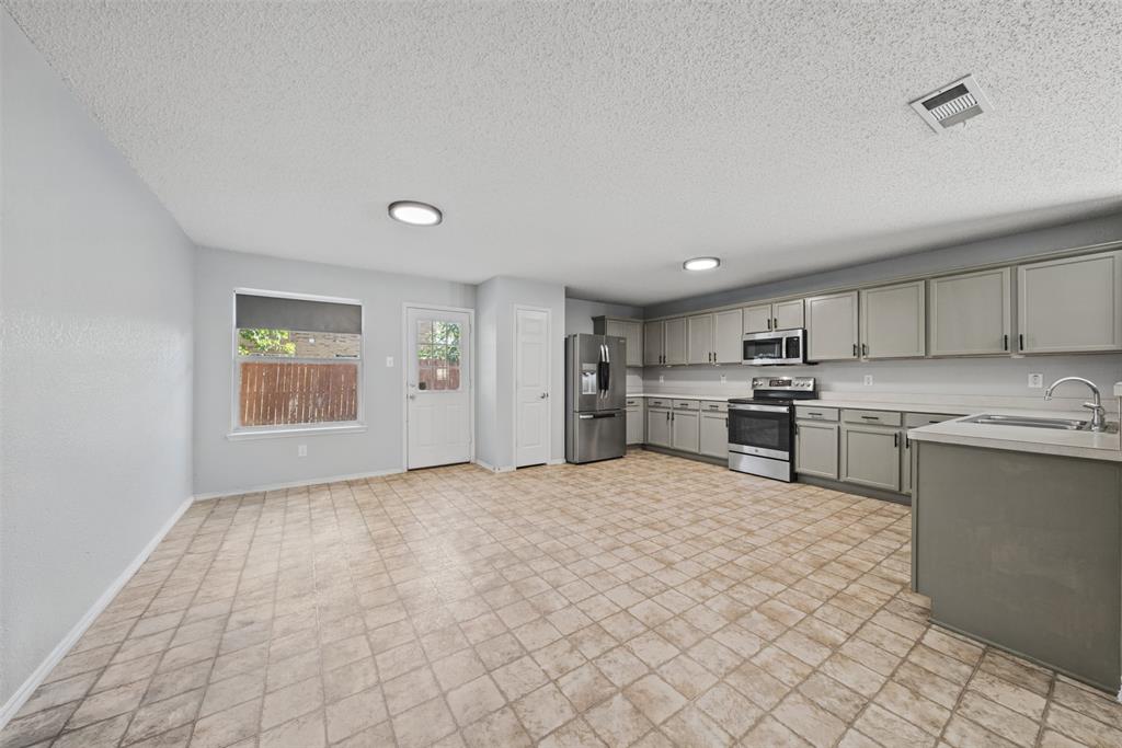 Kitchen featuring gray cabinetry, stainless steel appliances, ceramic tile flooring, and integrated lighting