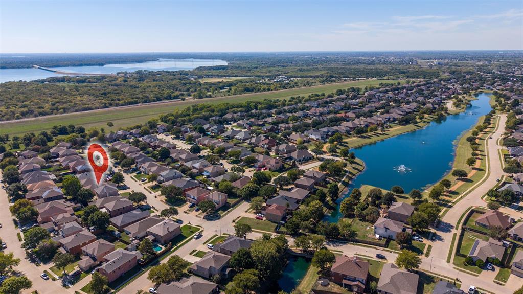 Aerial perspective showcasing a residential property with proximity to a community lake and established neighborhood landscaping