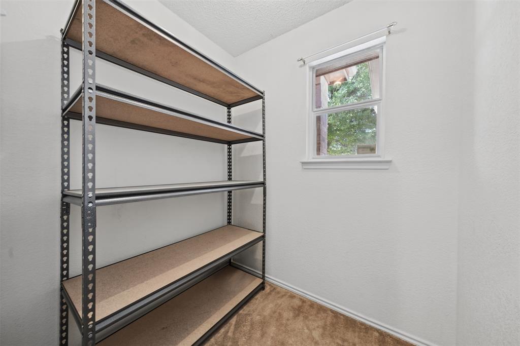 Interior space featuring neutral wall tones, carpeting, and a single-hung window with a roller shade