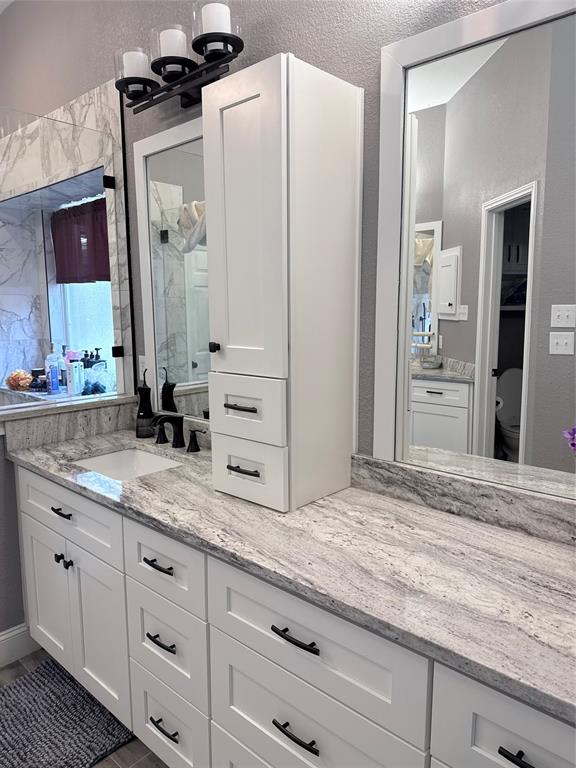 Double vanity featuring white cabinetry, stone-surface countertops, integrated under-mount sinks, matte black hardware, and framed wall mirrors