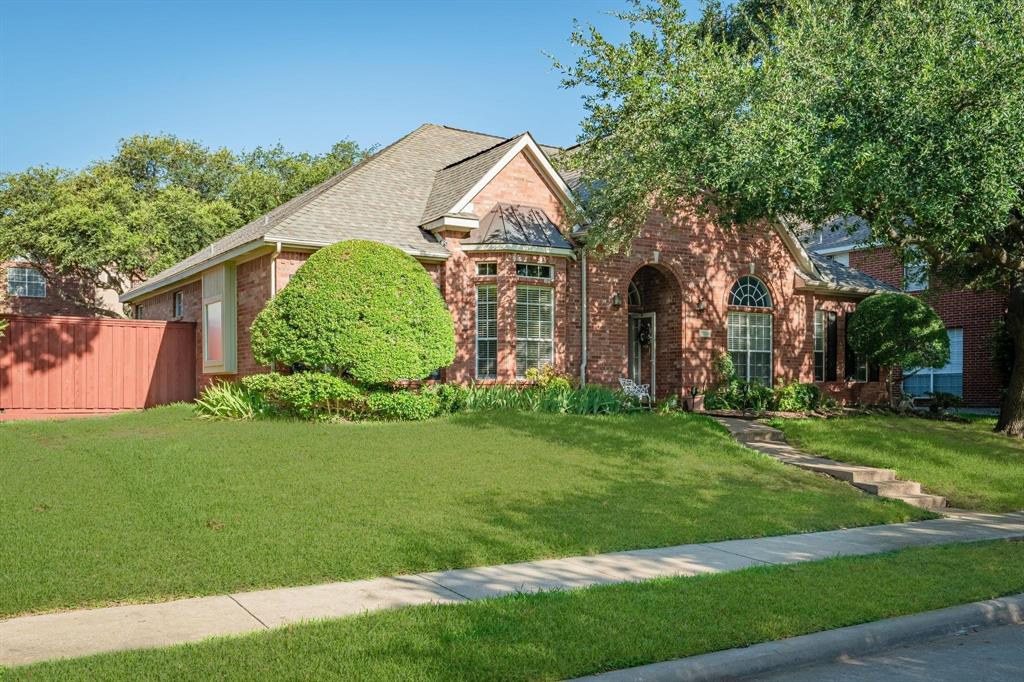 Traditional brick exterior featuring an arched entryway, gabled roofline, arched windows, and manicured landscaping