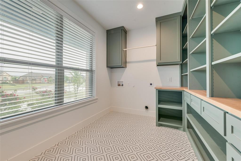 Custom sage-toned built-in cabinetry, wood-surface folding counter, geometric pattern tile flooring, and large window with integrated blinds