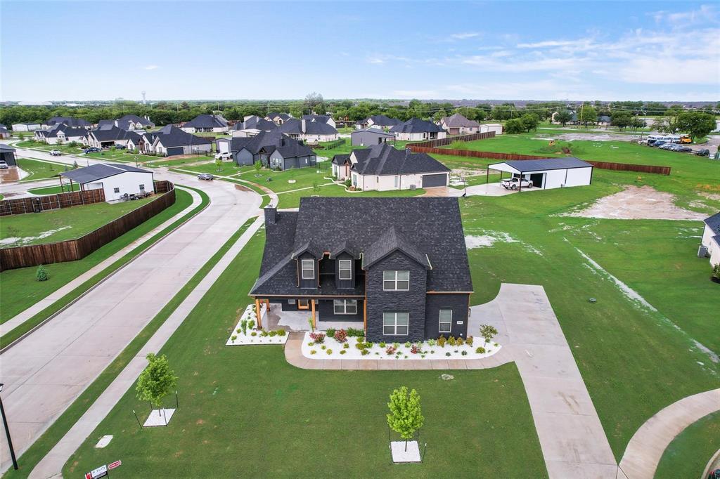 Aerial perspective of a corner lot featuring a multi-gabled roofline, concrete driveway, and established landscaping