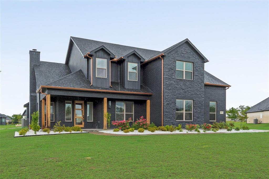 Two-story exterior featuring a dark brick facade, vertical siding, copper gutters, natural wood posts, and a shingled roof