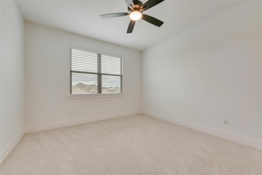 Neutral-toned carpeting, high-gloss white walls, dual-pane window with blinds, and a multi-blade ceiling fan with integrated lighting
