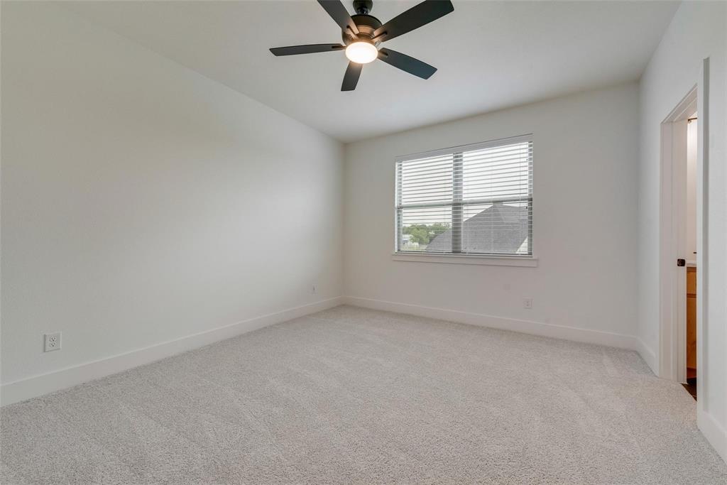 Neutral-toned carpeted flooring, window with horizontal blinds, and a central ceiling fan with integrated lighting