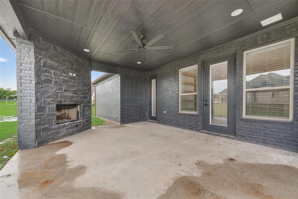 Dark-toned brick exterior featuring a covered patio, dual chimneys, multi-gabled roofline, and an expansive lawn