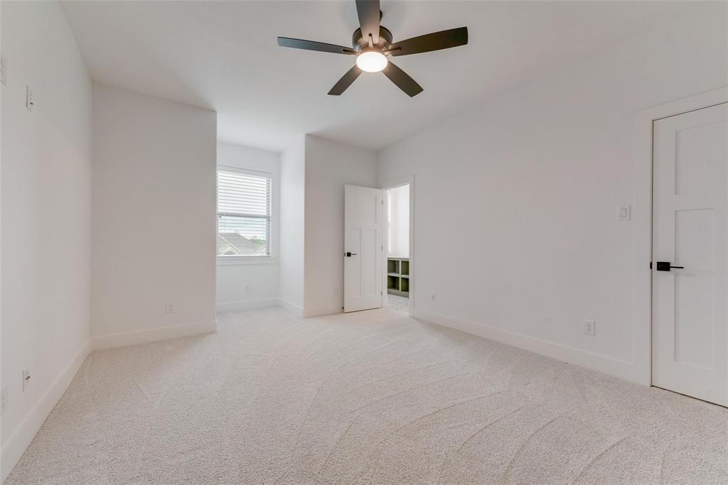 Neutral-toned wall-to-wall carpeting, ceiling fan with integrated lighting, window with horizontal blinds, and two-panel interior doors with matte black hardware