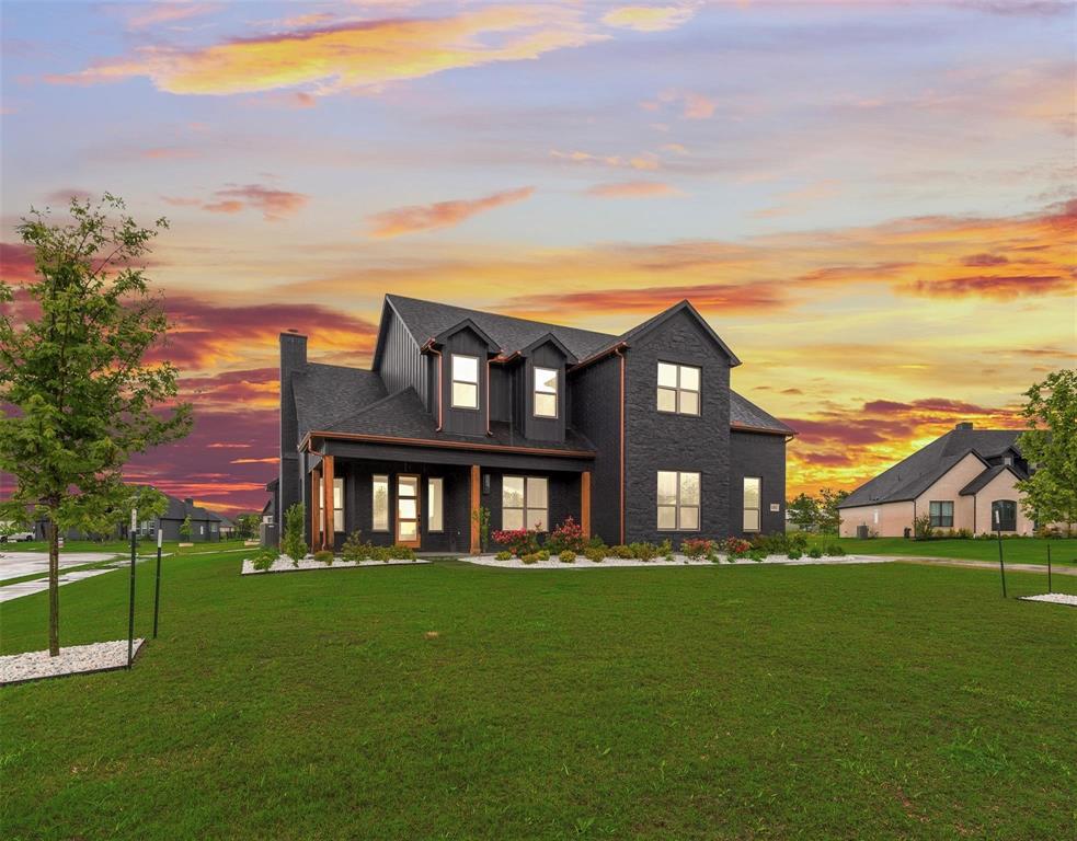 Two-story residence featuring a dark brick exterior, gabled roofline, prominent dormer windows, and a covered front porch with timber-finished support columns