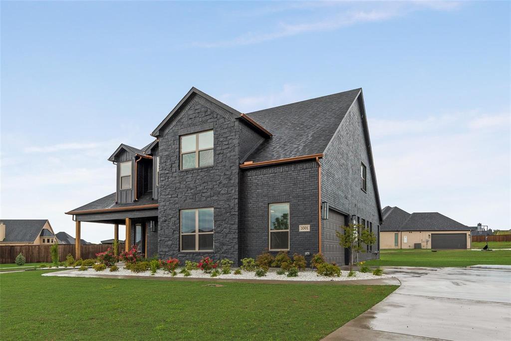 Two-story residence featuring a dark stone facade, multi-gabled roofline, covered porch, and concrete driveway