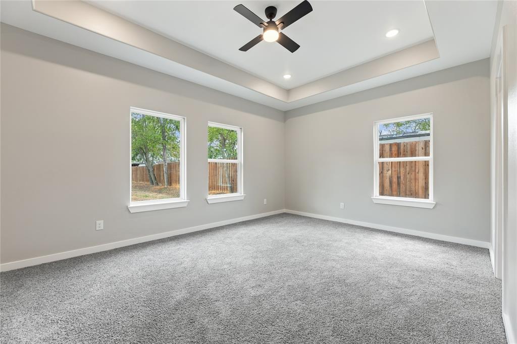 Tray ceiling with recessed lighting, central matte black ceiling fan, and multiple windows providing natural light