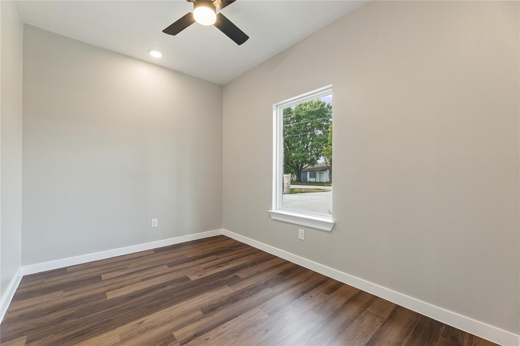 Neutral-toned interior featuring wood-finish flooring, a single-hung window with a sill, a ceiling-mounted light fixture with fan blades, and a recessed ceiling light