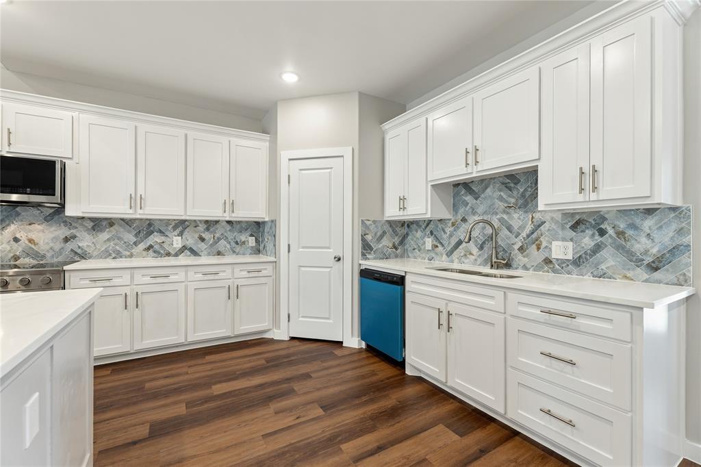 Kitchen featuring white shaker-style cabinetry, herringbone-pattern tile backsplash, wood-finish flooring, stone-surface countertops, and brushed nickel hardware