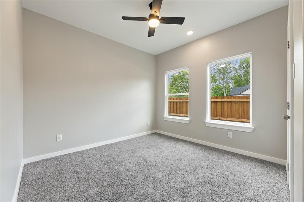 Room featuring neutral wall paint, plush carpeting, a modern ceiling fan with integrated lighting, and dual windows