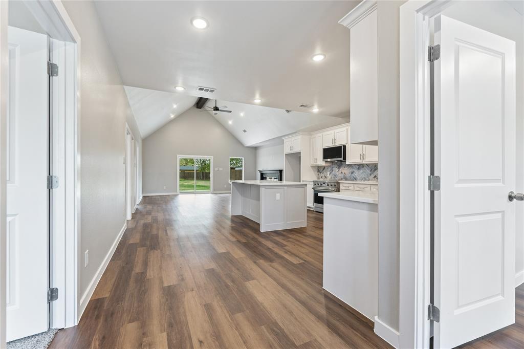 Open-concept floor plan featuring vaulted ceilings, wood-finish flooring, a central kitchen island, and recessed lighting