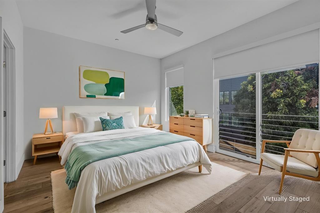 Wood-finish flooring, ceiling fan with integrated lighting, sliding glass door, and metal balcony railing