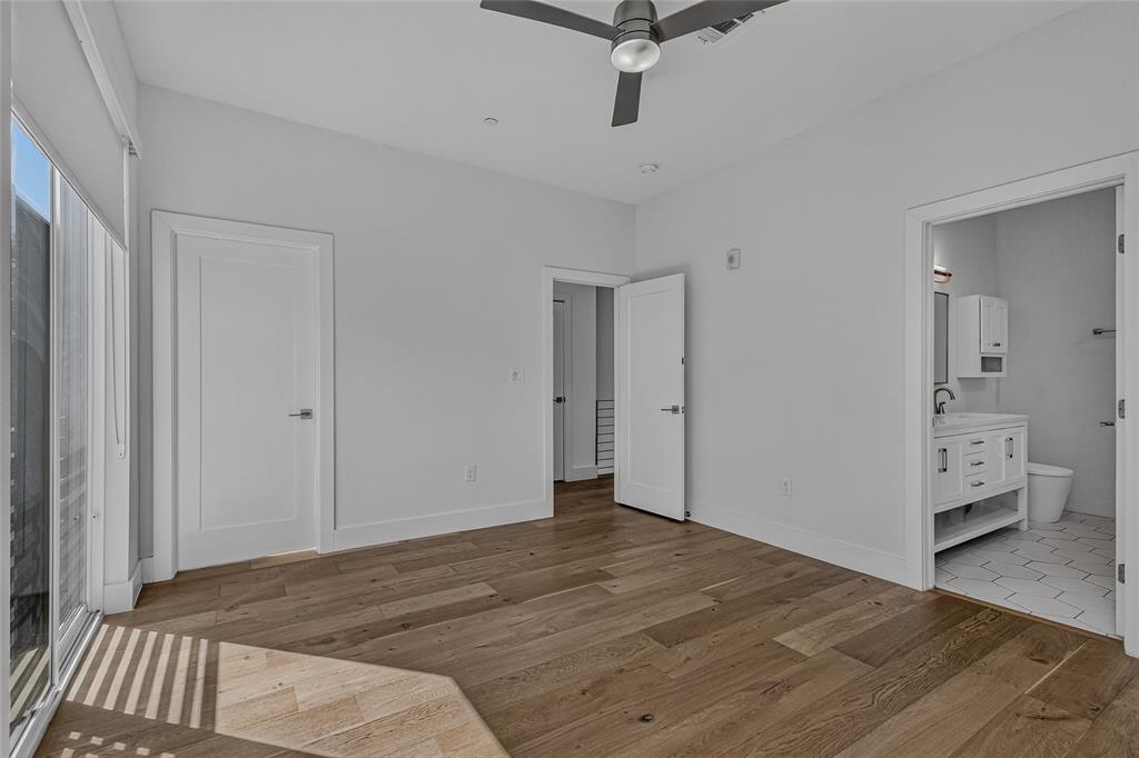Interior space featuring wood-finish flooring, a ceiling fan, sliding glass doors, and a bathroom equipped with a white vanity and hexagonal floor tile