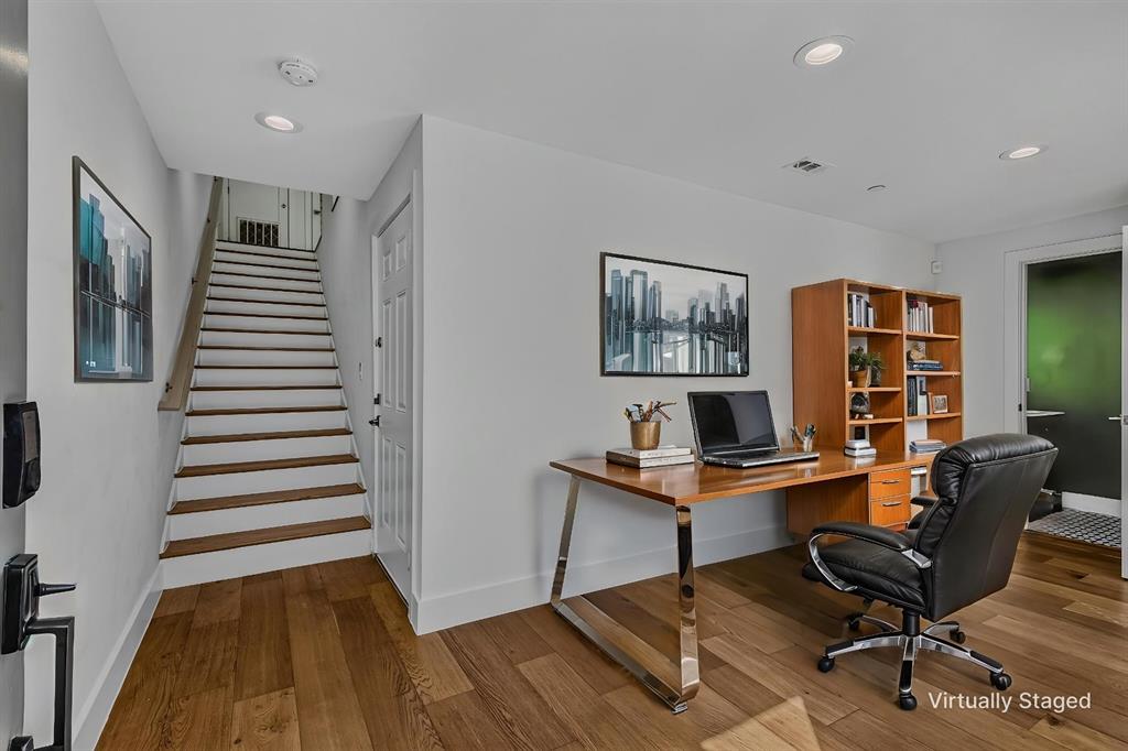 Wood-finish flooring, staircase with a wood-finished handrail, recessed lighting, and built-in shelving