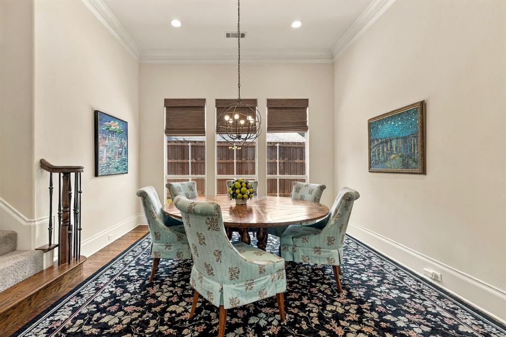 Dining area featuring high ceilings with crown molding, recessed lighting, a geometric orb chandelier, triple windows, and a wooden handrail with balusters