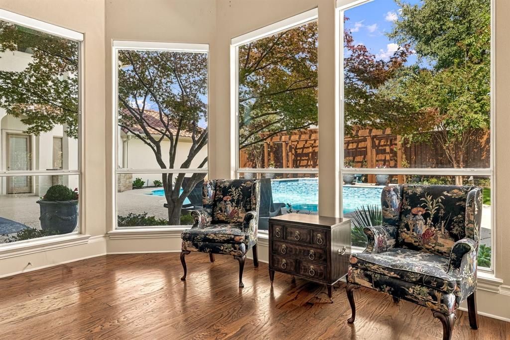 Bay window featuring large-pane glass, wood-finish flooring, and exterior exposure to a swimming pool, patio, and timber pergola