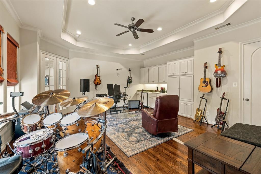 Tray ceiling with recessed lighting, wood-finish flooring, white built-in cabinetry, and French doors