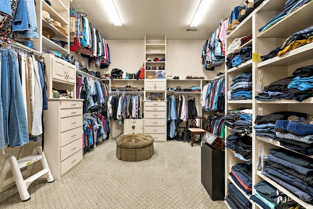 Walk-in closet featuring extensive built-in shelving, custom cabinetry with integrated drawer storage, and full-height hanging rods