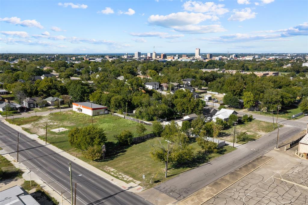 Aerial perspective of an expansive corner lot featuring street frontage on two sides and a backdrop of the urban skyline