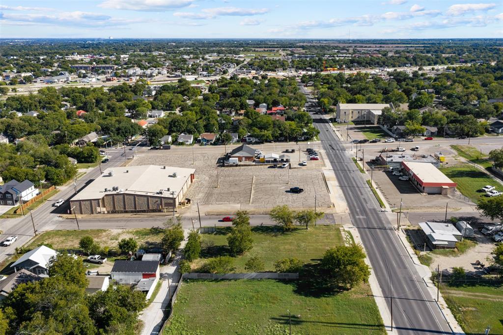 Aerial perspective of a corner lot featuring direct paved road access, expansive cleared terrain, and proximity to established commercial infrastructure