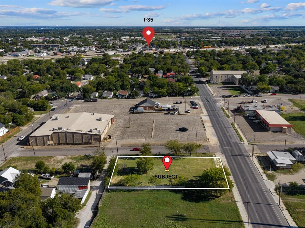Cleared vacant lot featuring street-front access, mature trees, and proximity to I-35