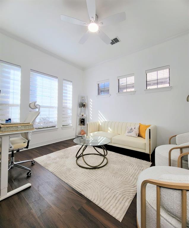 Room featuring dark wood-finish flooring, a neutral color palette, three large windows, three transom windows, and a ceiling fan with integrated lighting Room featuring dark wood-finish flooring, a neutral color palette, three large windows, three transom windows, and a ceiling fan with integrated lighting